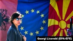 Žena prolazi pored zastava Albanije, EU i Severne Makedonije na pijaci u Skoplju, 3. februara 2020.