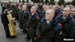 Un preot ortodox binecuvântează militari in Kiev.