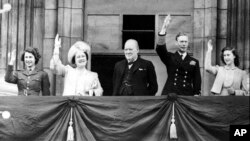 Prințesa Elisabeta, Regina Elisabeta, Regele George al VI-lea și Prințesa Margareta, pe balconul Palatului Buckingham, Londra, 8 mai 1945. În centrul imaginii se află prim-ministrul Marii Britanii Winston Churchill