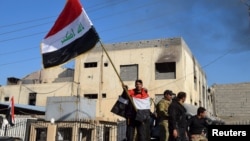 Иракский военный держит флаг в центре Рамади
