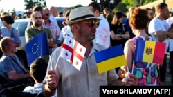 A man holds flags of the European Union, Georgia, Ukraine, and Moldova at a rally in support of Georgia's EU membership bid in central Tbilisi on June 16.