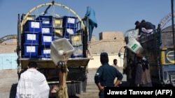 Afghan employees of the Independent Election Commission unload ballot boxes at a polling station ahead of the election in Kandahar Province on October 26.