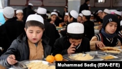 FILE: Afghan orphans, who lost their parents in conflicts, eat a meal at Sheikh Mohammed Bin Rashid al-Maktoum orphanage house, in the southern Afghan city of Kandahar.