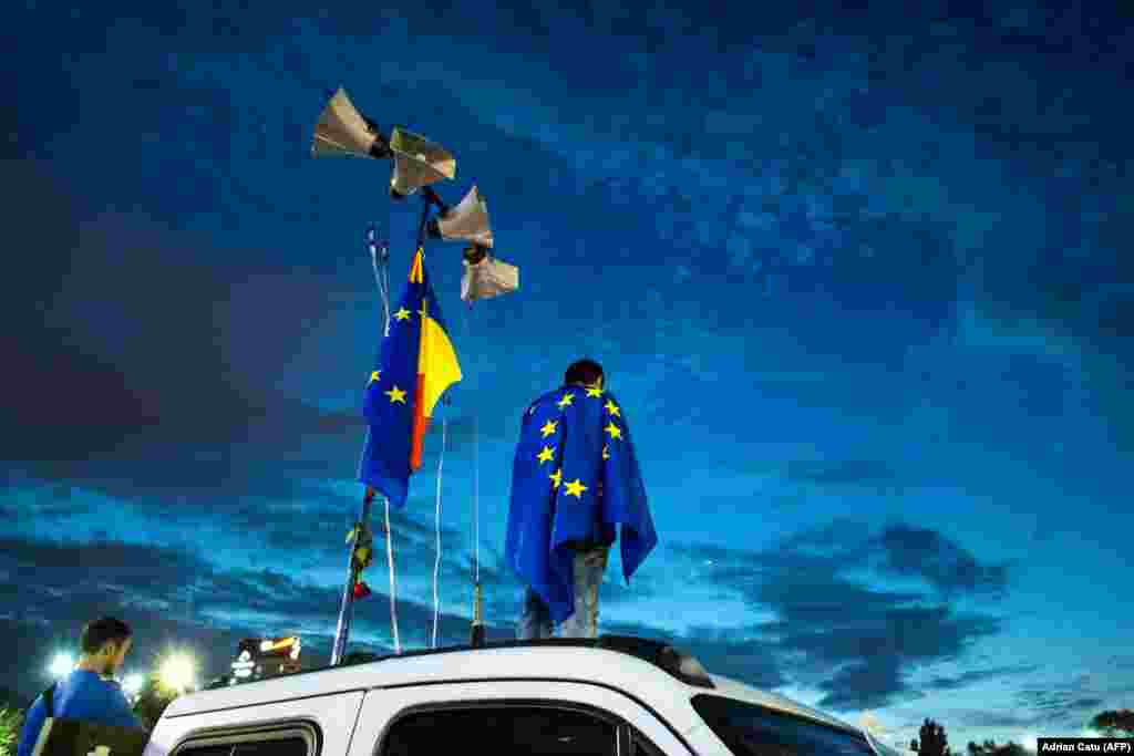 A man stands on a truck draped in an EU flag as demonstrators gather in front of the Romanian prime minister's office at an anticorruption rally in Bucharest. (AFP/Adrian Catu)