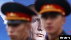 Navy sailors walk past an election billboard for Putin's party in St. Petersburg in September 2011