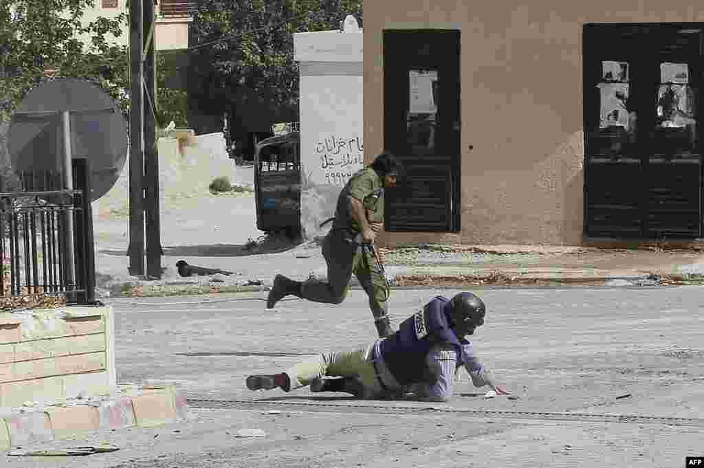 AFP reporter Sammy Ketz hits the ground as a Syrian soldier runs past during sniper fire in the ancient Christian Syrian town of Maalula. (AFP/Anwar Anro)