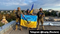 Украинские военные с национальным флагом на крыше здания в Купянске, Харьковская область, 10 сентября 2022 года
