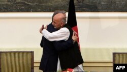 Abdullah Abdullah and Ashraf Ghani embrace after signing a power-sharing agreement at the Presidential Palace in Kabul, September 21, 2014.