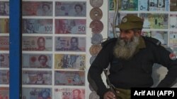 FILE: A security guard sits outside the currency exchange shop in the eastern Pakistani city of Lahore.