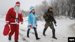Волонтери, переодягнені в костюми Діда Мороза та Снігуроньки, разом з українським військовослужбовцем біля Лисичанська. Січень 2015 року. Ілюстративне фото