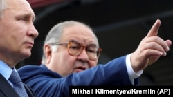 Uzbek-born Russian businessman Alisher Usmanov (left) has been included on a list of people with close links to President Vladimir Putin (right) who may the subject of future U.S. sanctions. (file photo) 