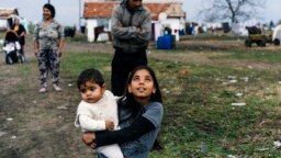 A Romany girl carries her brother on a street in the Bulgarian village of Ekzarh Antimovo.