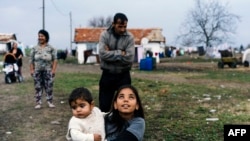 Egy roma lány viszi a testvérét a lepusztult Egzar Antimovo faluban