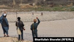 Afghan policemen wave at Taliban fighters in a remote frontline in the southern province of Uruzgan on February 25.