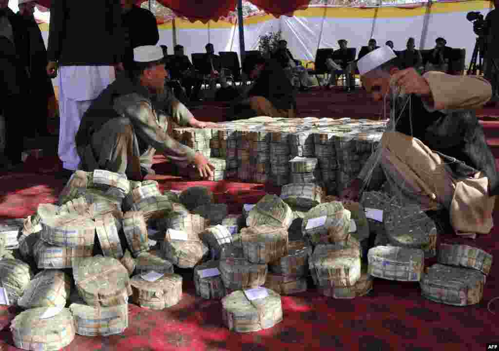 Afghan officials count and adjust bundles of the Afghan currency, the afghan, before setting the notes on fire in Jalalabad, in Nangarhar Province. (AFP/Noorullah Shirzada)