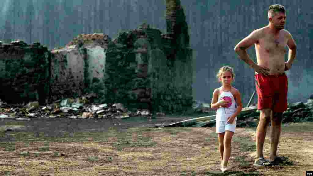 Residents stand near a burned home one day after a wildfire raged in the village of Gornja Gorevnica, near Cacak, Serbia. (EPA/Aleksandar Stankovic)