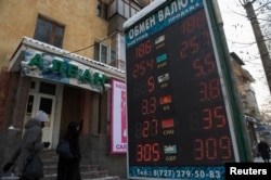Люди проходят мимо пункта обмена валют. Алматы, 11 февраля 2014 года.