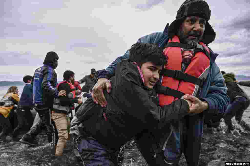 Чоловік допомагає хлопцеві вийти з човна з 54 афганськими біженцями, які причалили до берегів грецького острова Лесбос 28 лютого