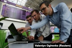 Technicians work on a flight timetable for the website of Ukraine's Boryspil Airport near Kyiv following a cyberattack on June 27 that started in Ukraine before spreading elsewhere.