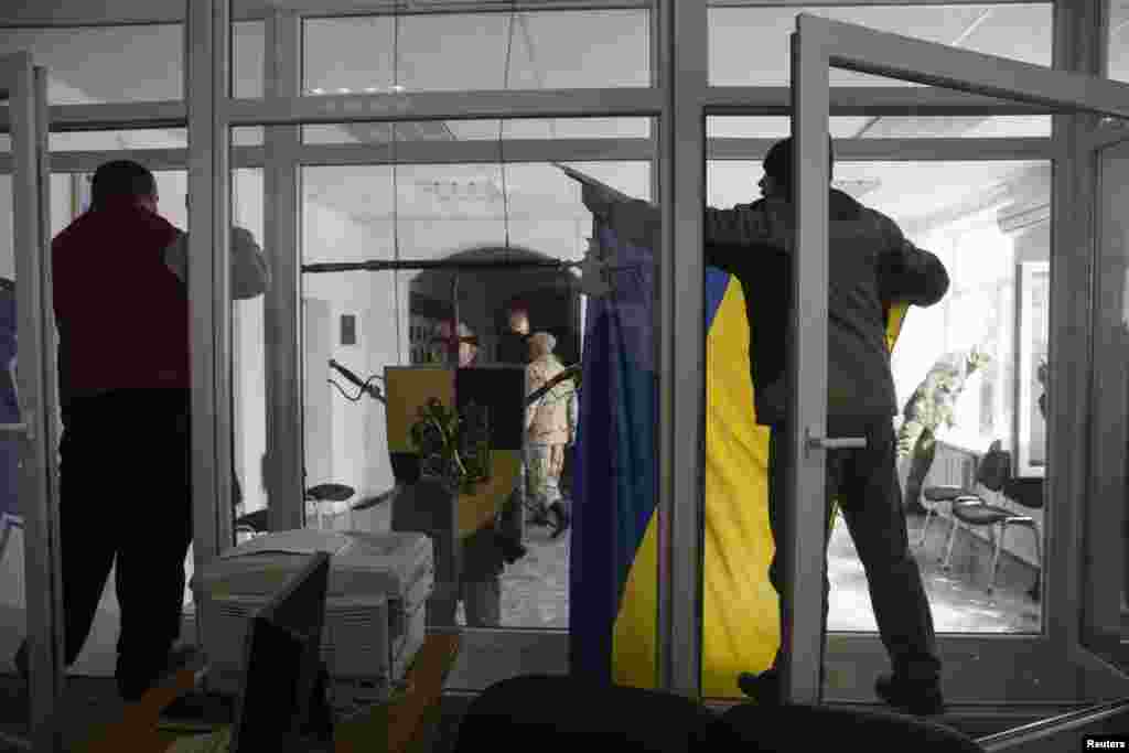 Ukraine -- A pro-Russian supporter takes down a Ukrainian flag after breaking into the territory of the naval headquarters in Sevastopol, March 19, 2014