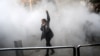 An Iranian woman raises her fist amid the smoke of tear gas at the University of Tehran during a protest driven by anger over economic problems in December 2017.