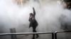 An Iranian woman raises her fist amid the smoke of tear gas at the University of Tehran during a protest driven by anger over economic problems in the capital on December 30.