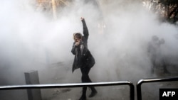 An Iranian woman raises her fist amid the smoke of tear gas at the University of Tehran during a protest driven by anger over economic problems in the capital on December 30.