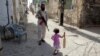 A girl with a cricket bat walks past a militant in Rahim Yar Khan, southern Punjab Province (file photo)