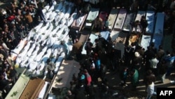 A handout picture obtained from Syrian opposition activists in Homs shows mourners gathered around coffins and bodies during a mass funeral in the city of Homs on February 4.