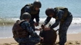 Ukrainian soldiers defuse an anti-ship mine thrown ashore by a storm in 2022.