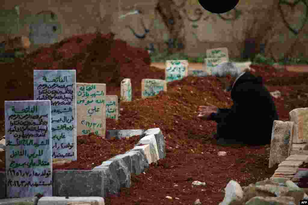 A Syrian man mourns at the graves of relatives in a rebel-held area of the city of Daraa in southern Syria. (AFP/Mohamad Abazeeed)