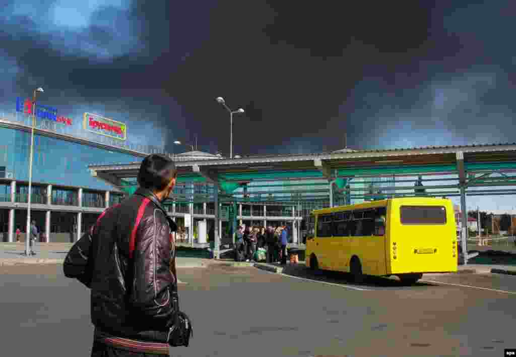 A man looks at black smoke rising behind a building of the international airport in Donetsk on&nbsp;October 2. (epa/Photomig) 