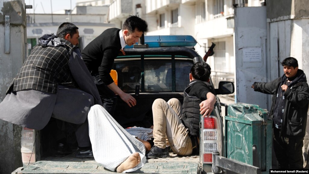 Men carry an injured person to the hospital after attacks in Kabul on March 7.