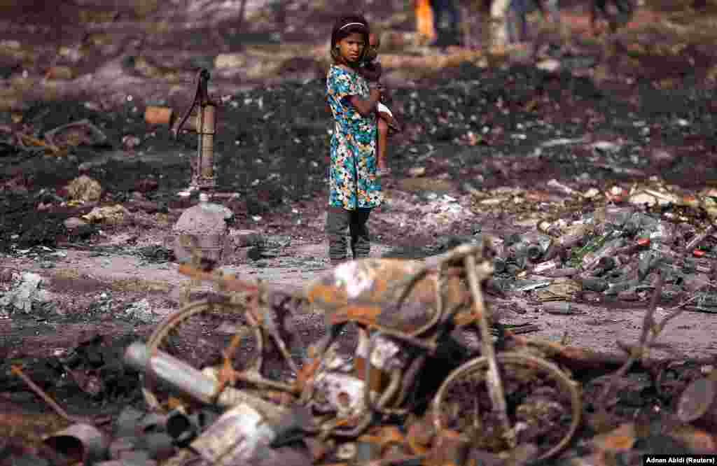 A girl carries her brother as she stands near her burnt home after a fire broke out in a slum area in New Delhi on April . (Reuters/Adnan Abidi) 
