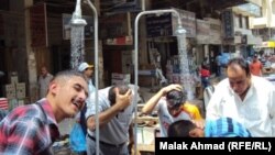 Iraq - Men refresh themselves under shower in street, Baghdad, undated