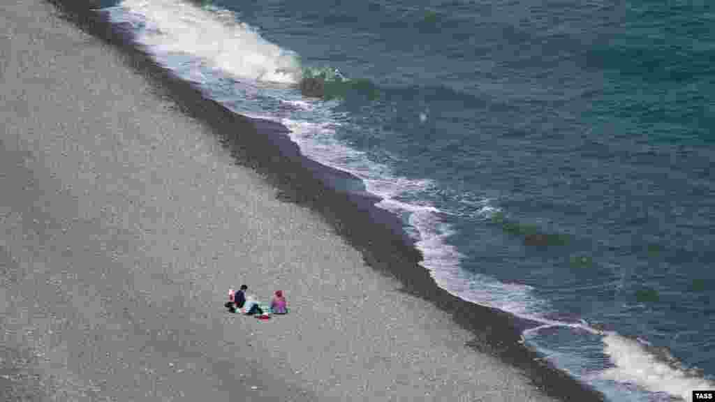 Поодинокі відпочивальники на березі моря в Рибачому