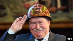 Fostul președinte al Poloniei Lech Walesa pozând cu o cască Euromaidan în cadrul unei ceremonii din Gdansk