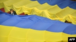 A deputy sits next to huge Ukrainian flags decorating the benches of opposition deputies who left a parliamentary session in June to protest a language bill.