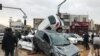 IRAN -- People stand near destroyed cars after a flood hit the city of Shiraz, March 25, 2019