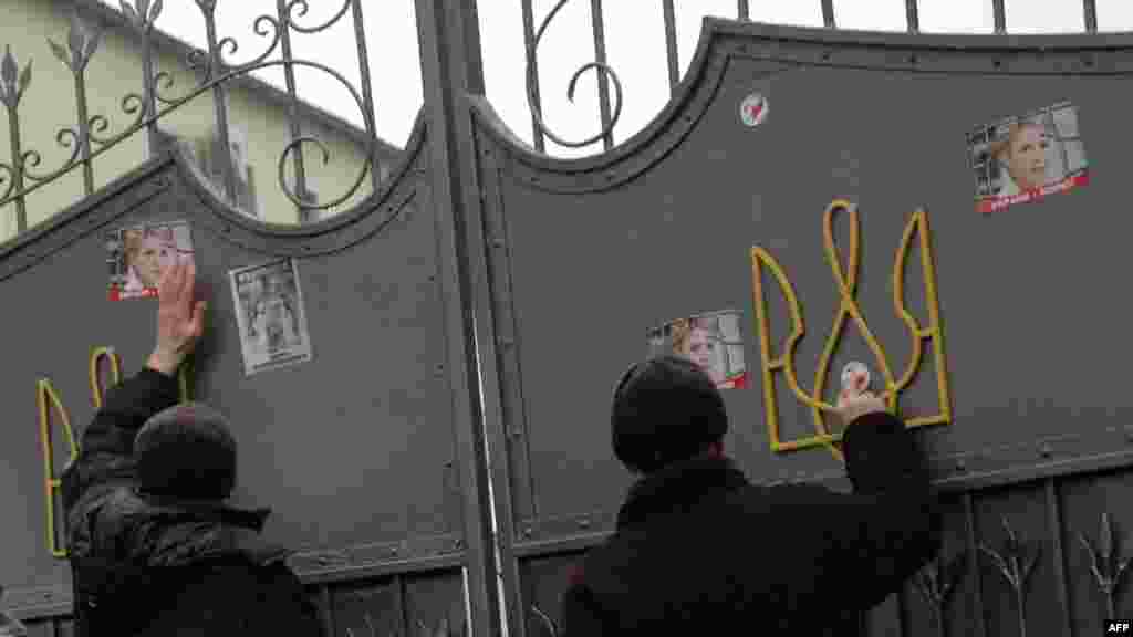 Supporters of jailed former Ukraine Prime Minister Yulia Tymoshenko attach her portrait to the gate of the women's prison where she's being held. AFP PHOTO/ MIKHAIL KUCHNEV
