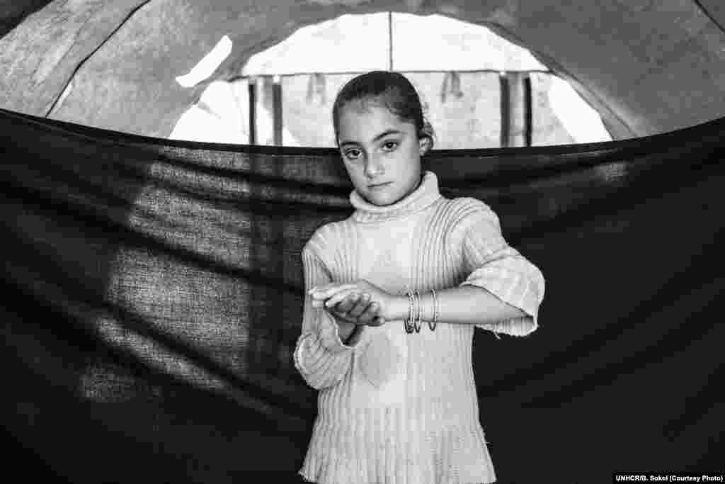May*, 8, poses for a portrait in Domiz refugee camp in the Kurdistan Region of Iraq on 16 November 2012. She and her family arrived in Domiz about one month before this photograph was taken, having fled their home in Damascus. Since arriving in Domiz, she has had recurring nightmares in which her father is violently killed. She is now attending school, and says she finally feels safe. May hopes to be a photographer when she grows up. The most important thing she was able to bring with her when she left home is the set of bracelets she wears in this photograph.