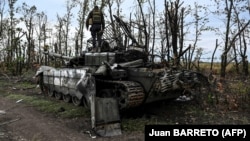 Украинские военные осматривают подбитый российский танк