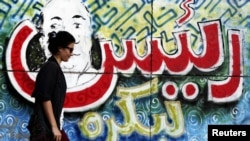 A woman walks in front of a wall near Tahrir Square in central Cairo on June 18 with graffiti reading "President for tomorrow."