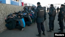 Russian police detain migrant workers during a raid on the Pokrovsky vegetable storage depot in the Biryulyovo district of Moscow on October 14, one day after the rioting sparked by the killing.