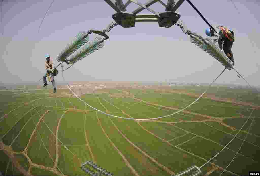 Electricians check a pylon situated amid farmland in China's Anhui Province. (Reuters/China Daily)