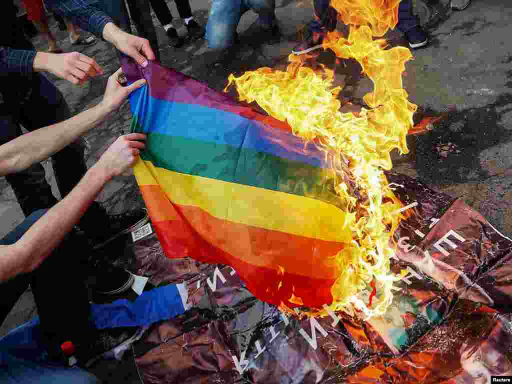 Kiýew, Pride-2017-niň açylyş dabarasynda anti-LGBT protestçileri LGBT baýdagyny ýakýarlar. 13-nji iýun. (Reuters/Gleb Garanich)