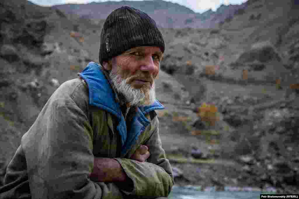 BORDER - road, access, construction, earthquake Tajik road worker squats on the side of the road. Afghanistan is in background Tajikistan