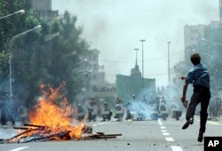 A student protester throws a stone at riot police near Tehran University during a clash which started when police occupied and closed the main entrance to the Tehran university Tuesday, July 13, 1999