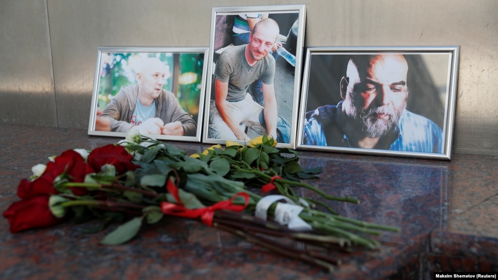 Photographs of journalists Orkhan Dzhemal (right), Kirill Radchenko (center) and Aleksandr Rastorguyev are seen at a small memorial to the slain jounalists outside the Central House of Journalists in Moscow.