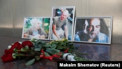 Photographs of journalists Aleksandr Rastorguyev (left), Kirill Radchenko (center), and Orhan Dzhemal are displayed outside the Central House of Journalists in Moscow in August.
